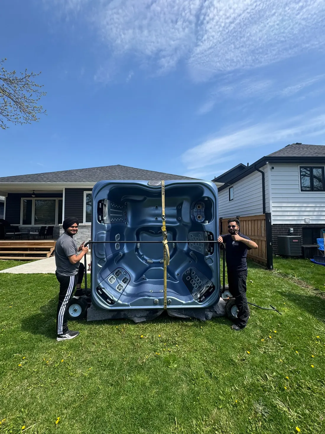 Hot tub strapped to a dolly in a backyard