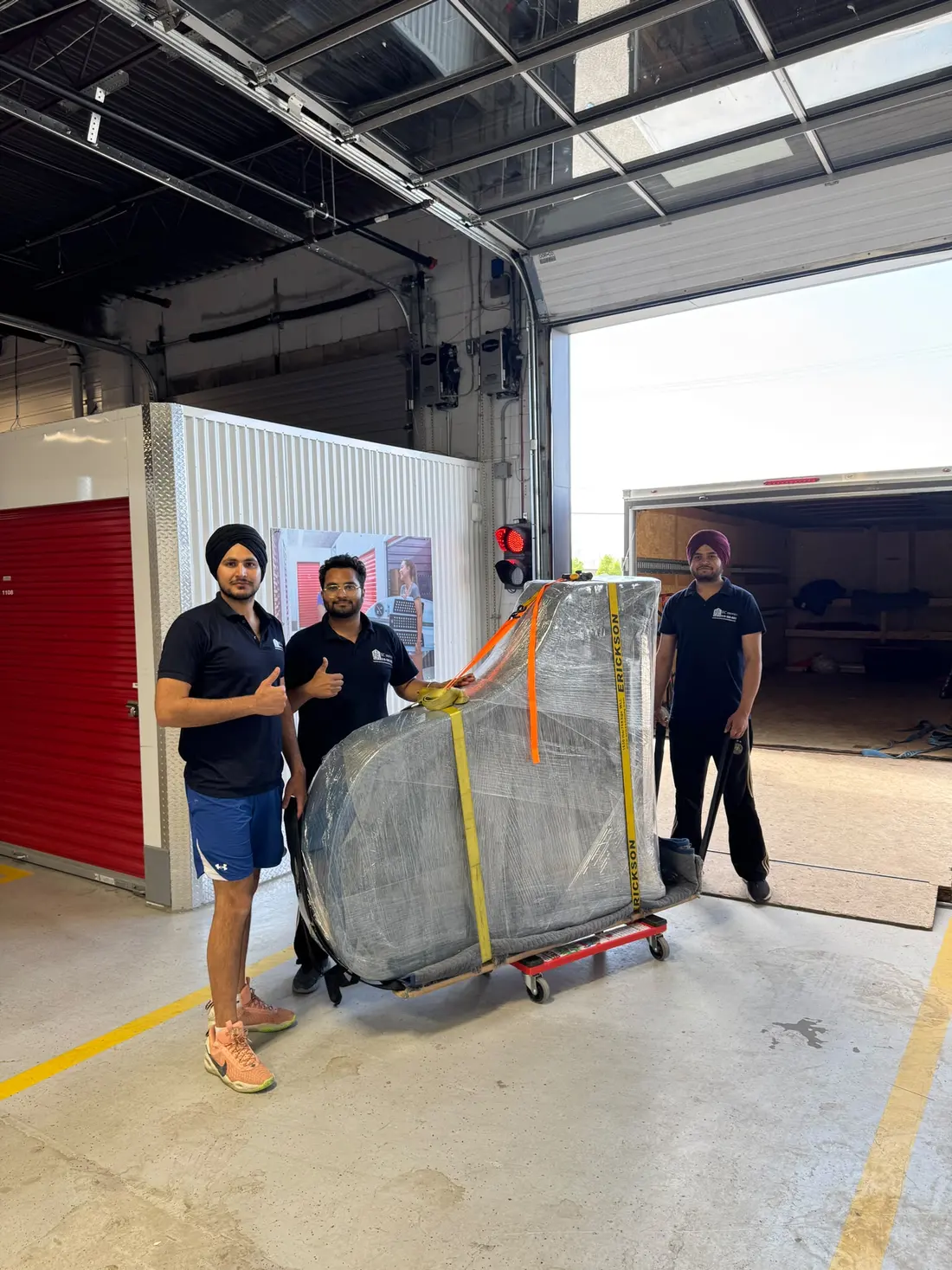 EC Movers crew with a wrapped grand piano on a dolly