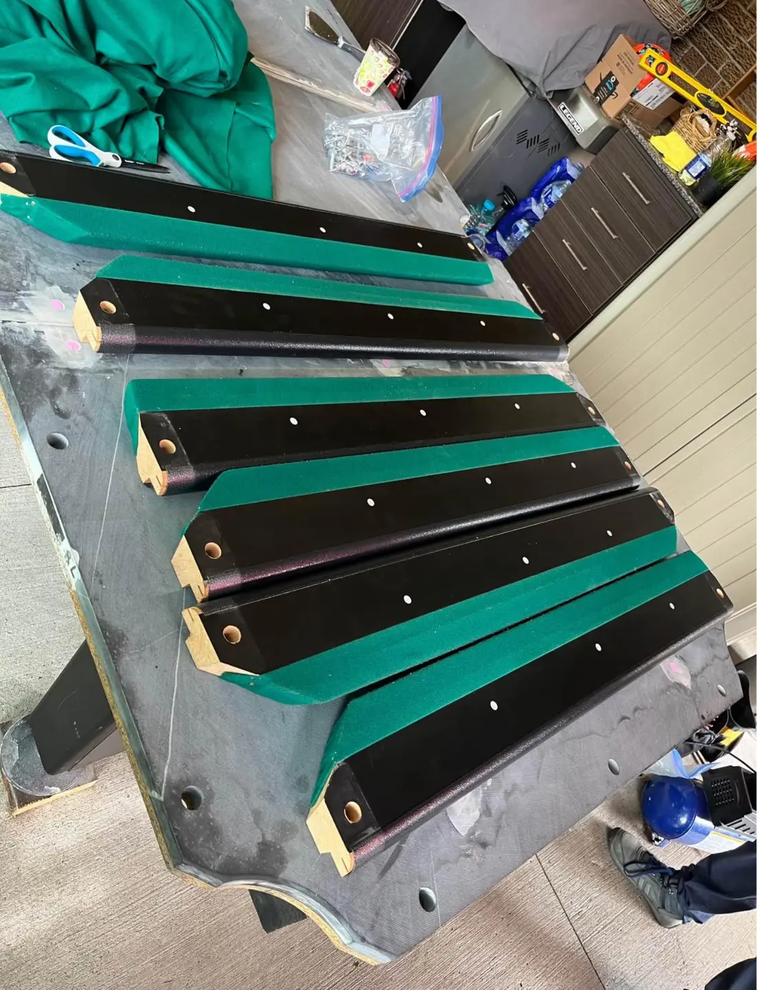 Pool table rails with new green cloth laid out during a re-cover