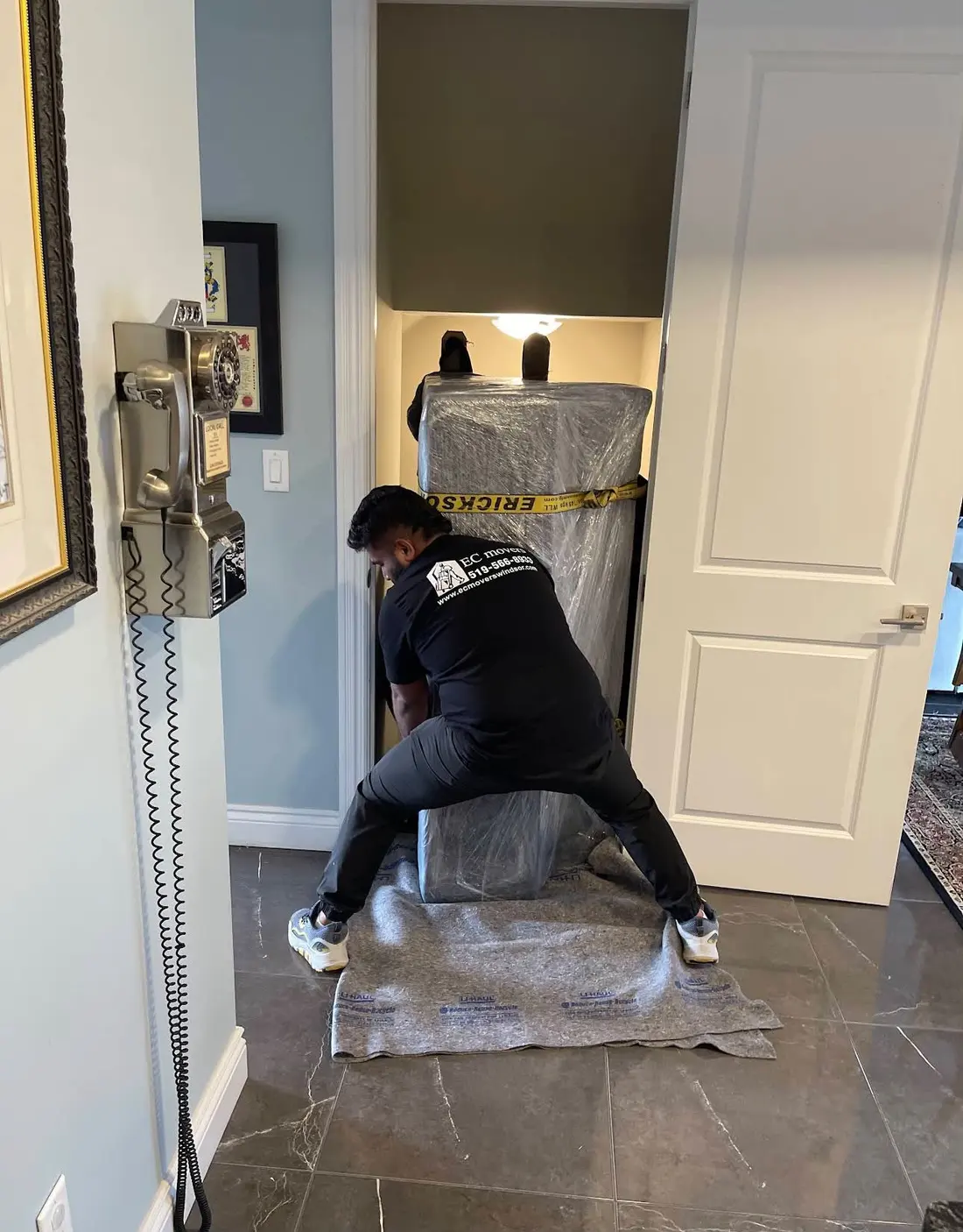 Mover guiding a wrapped cabinet through a doorway